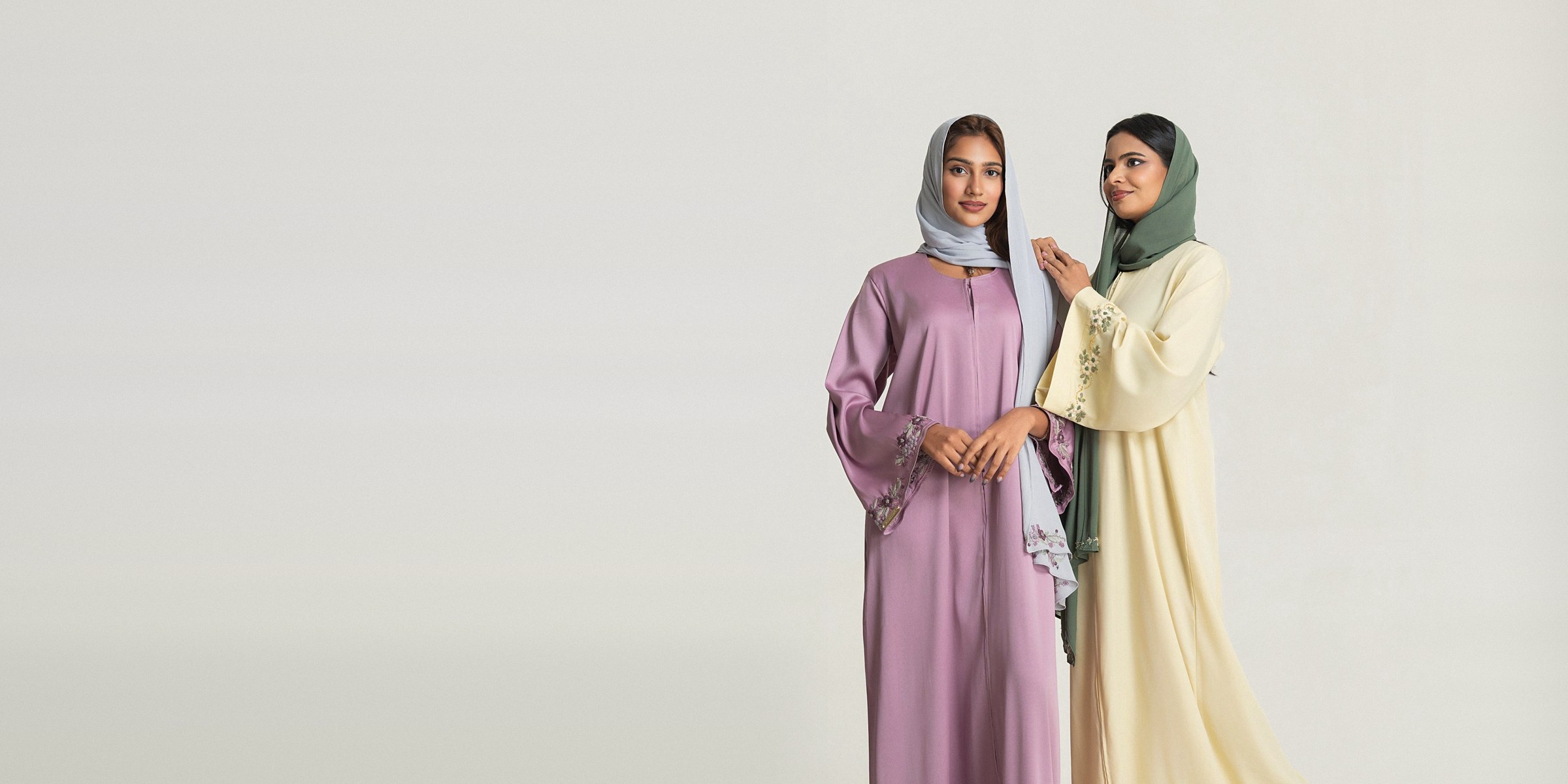 Two women in the Iris and Vanilla abaya sets, violet and buttercream, with embroidered hijabs